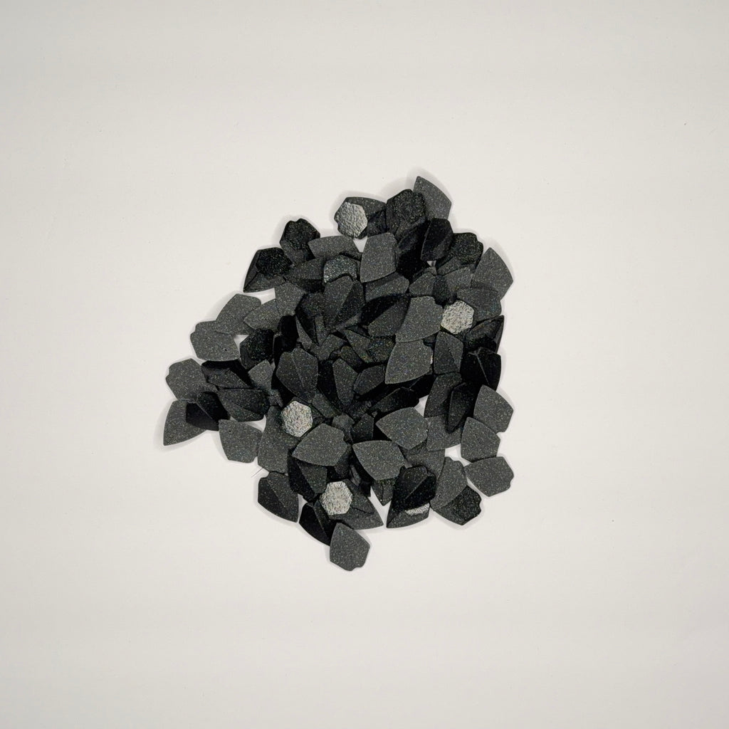 Speckled black loose dragon scales on a light gray background