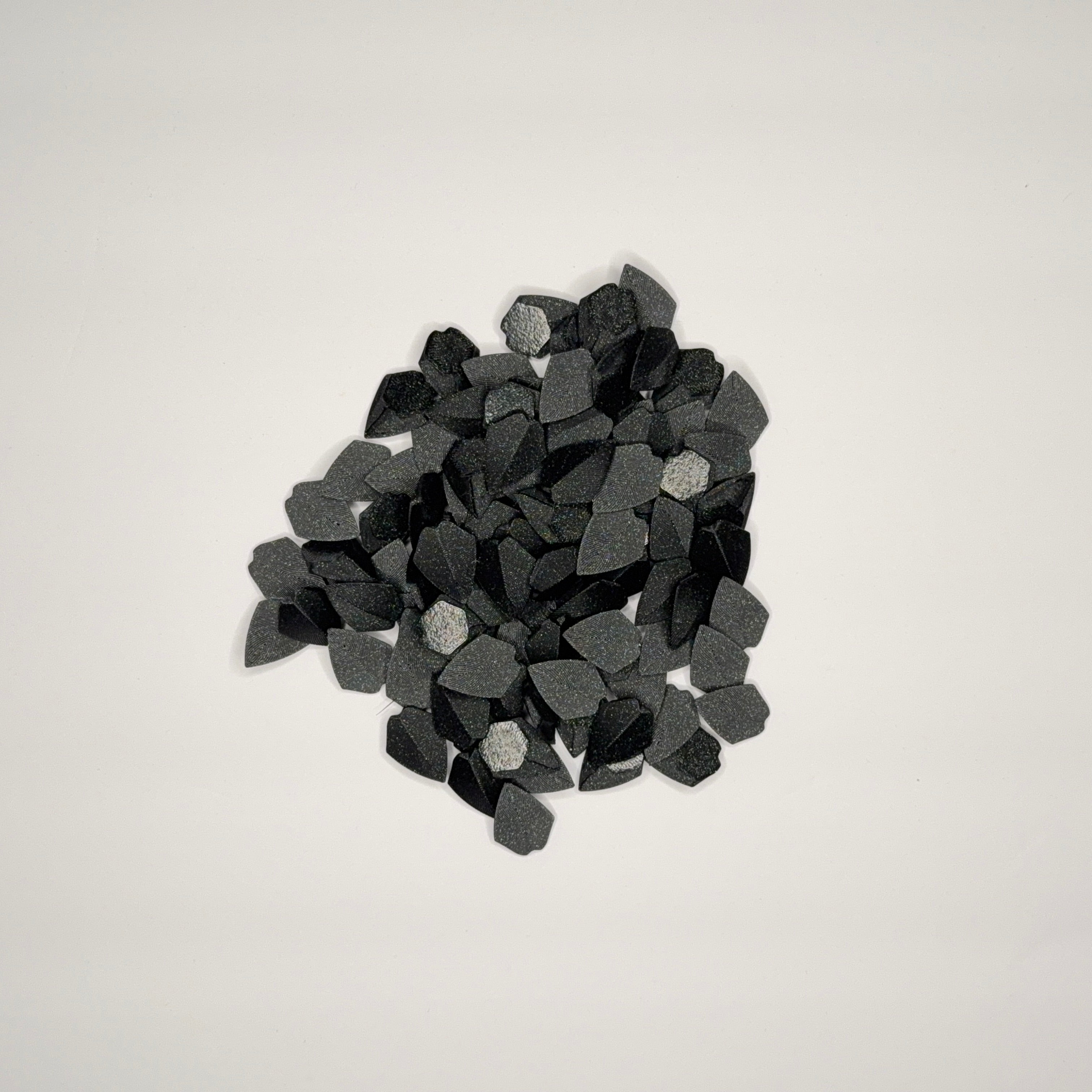 Speckled black loose dragon scales on a light gray background